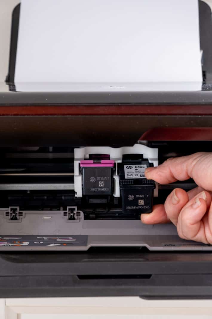 Hand removing black printer cartridge in inkjet printer.