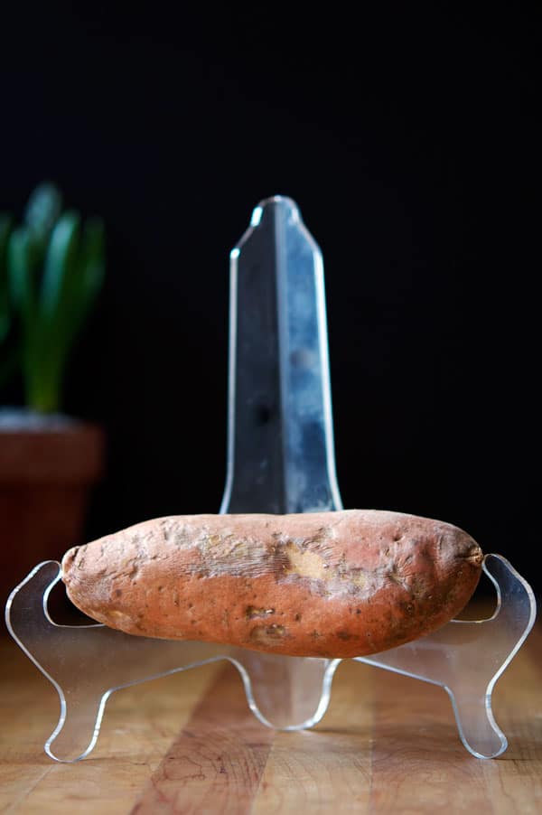 A chill damaged sweet potato showing signs of dark spots and blemishes from being too cold.