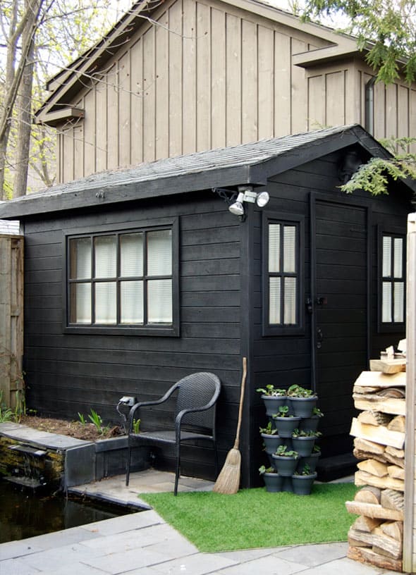 Black painted shed in slate backyard.