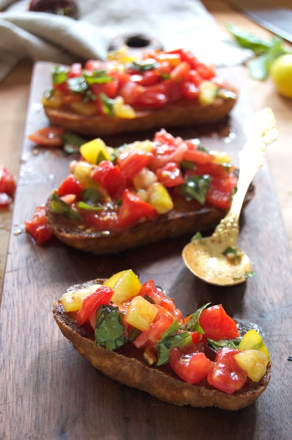 Julia Child's bruschetta with fried bread and marinated tomatoes on a wood cutting board.