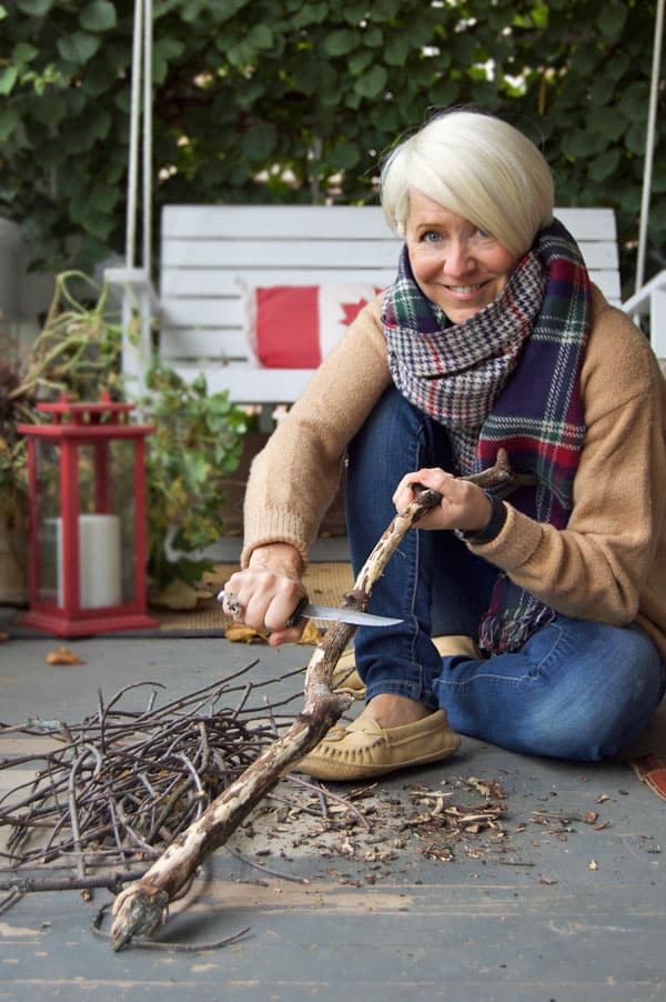 Karen Bertelsen carves a stick with a buck knife.