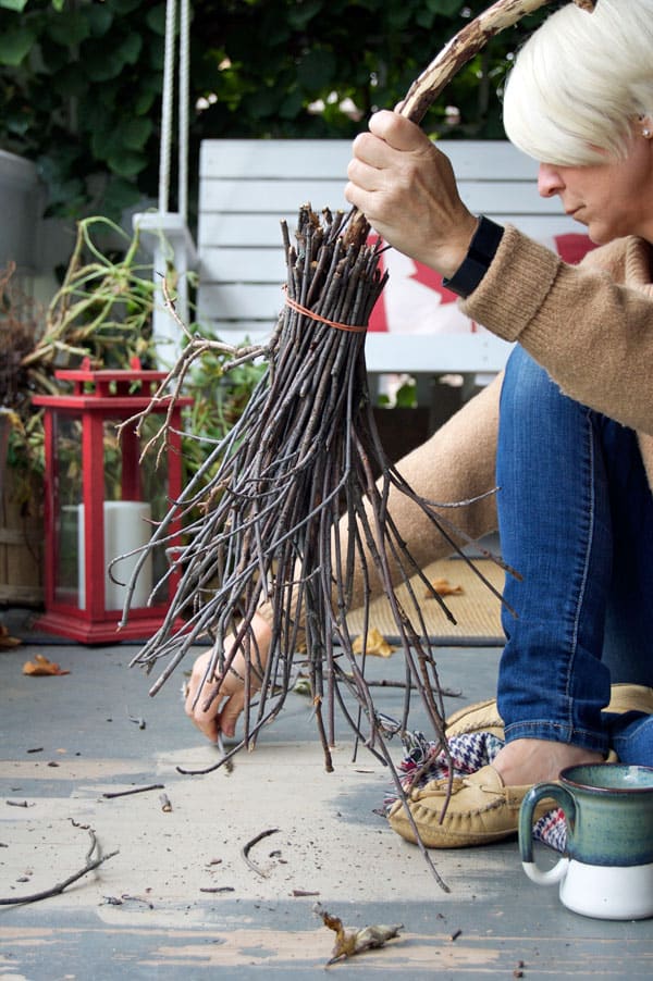 Halloween broom being held together with a red elastic band while forming the broom portion with twigs.