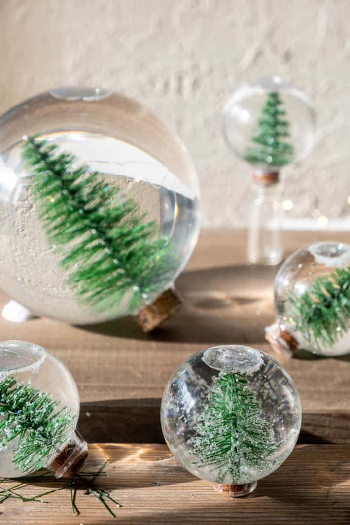 Simple home made snow globes with bottle brush trees laying on barn board. 