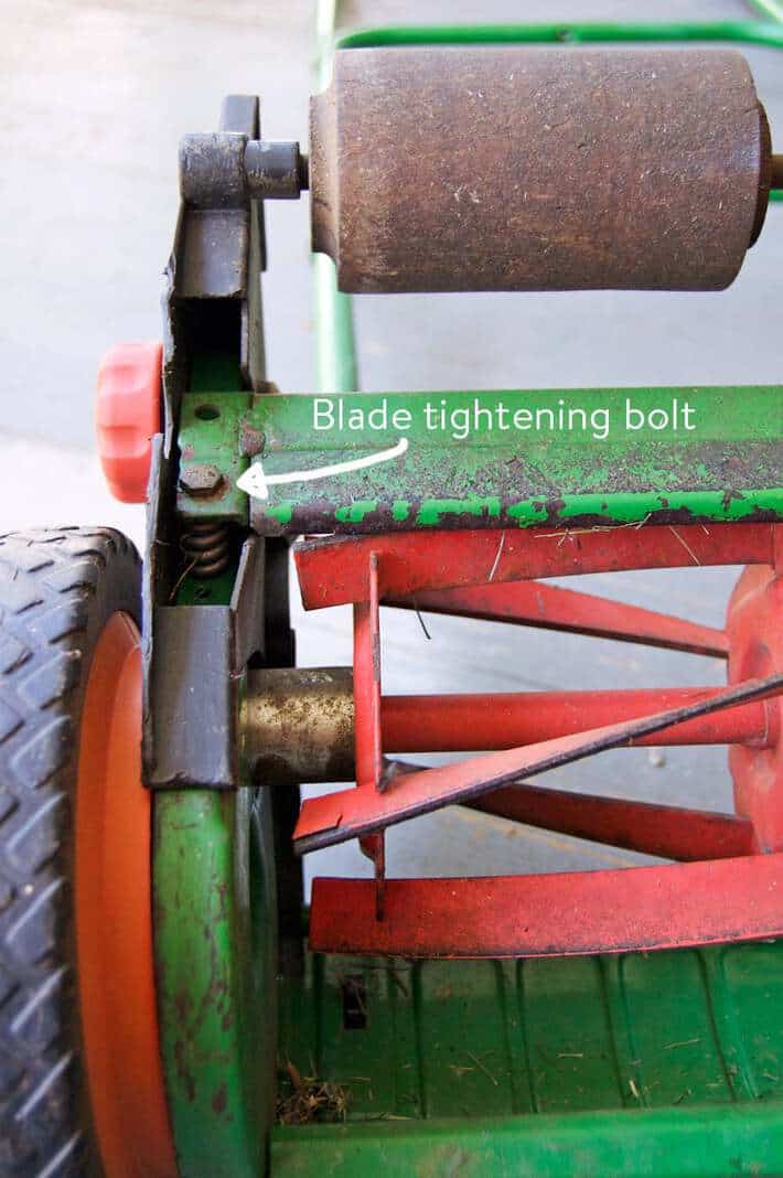 Blade tightening bolt to the left of the cutting bar on a push mower.