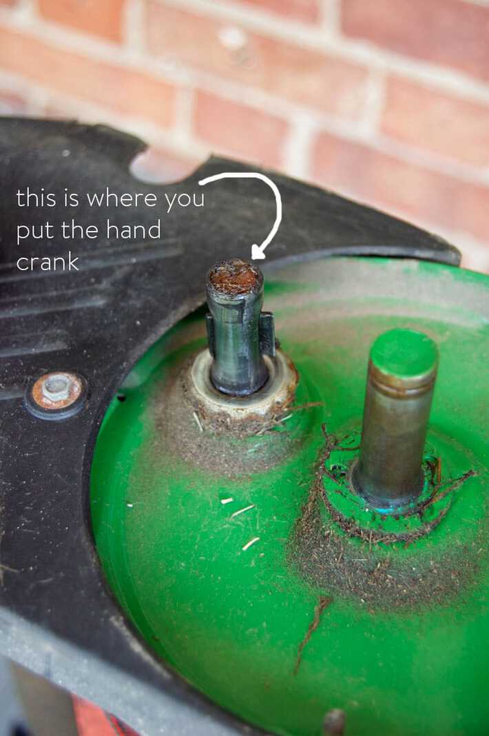 Green wheel well of a push mower, pointing out where you put the hand crank.