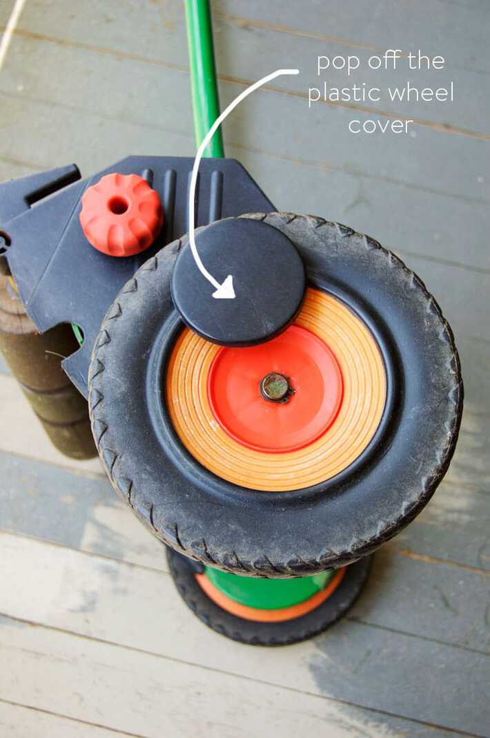 Removing the plastic wheel cover from a push mower wheel.