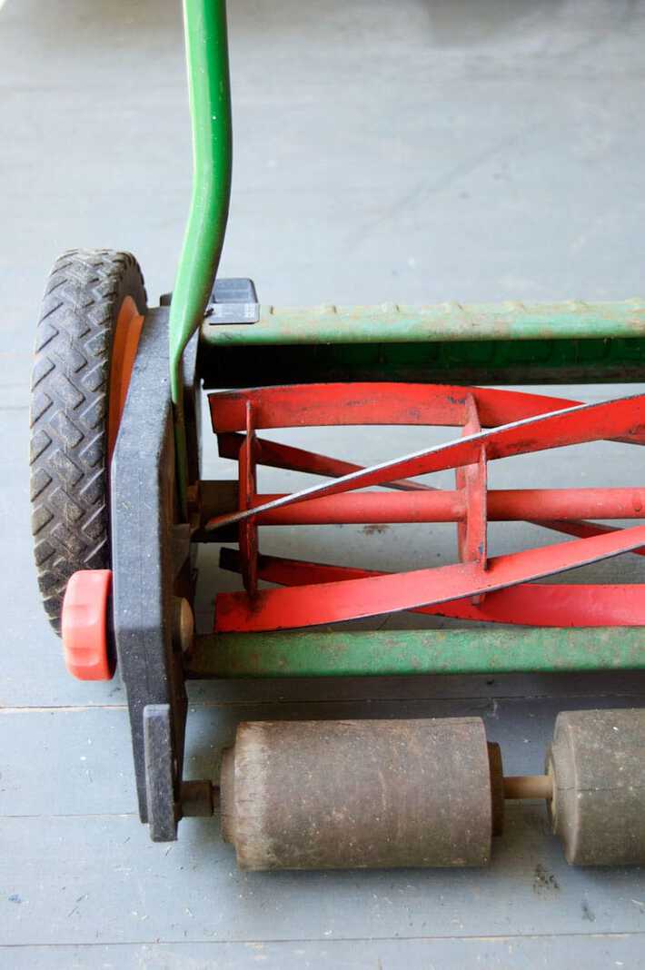 Freshly restored blades on a green and red push mower ready to roll.