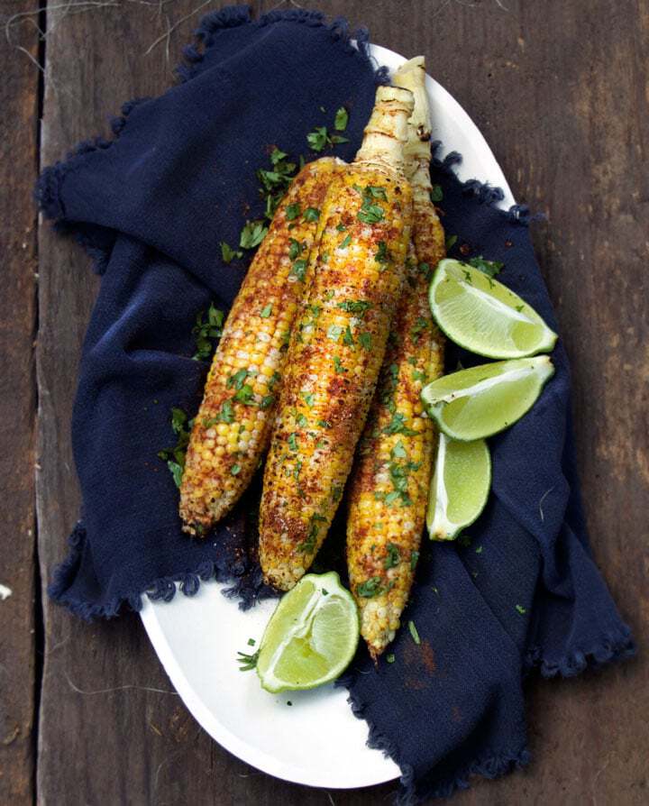 grilled corn on the cob with cilantro and lime on a platter.