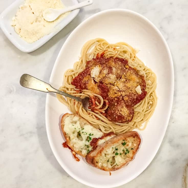 Spaghetti and meatballs in a contemporary pasta bowl on marble countertop.