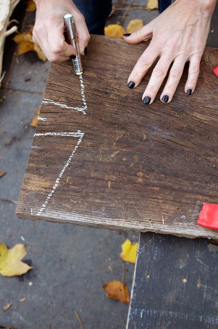Make your own "antique" wood serving board in about 2 hours. Marking a piece of barn board with chalk to make serving board.