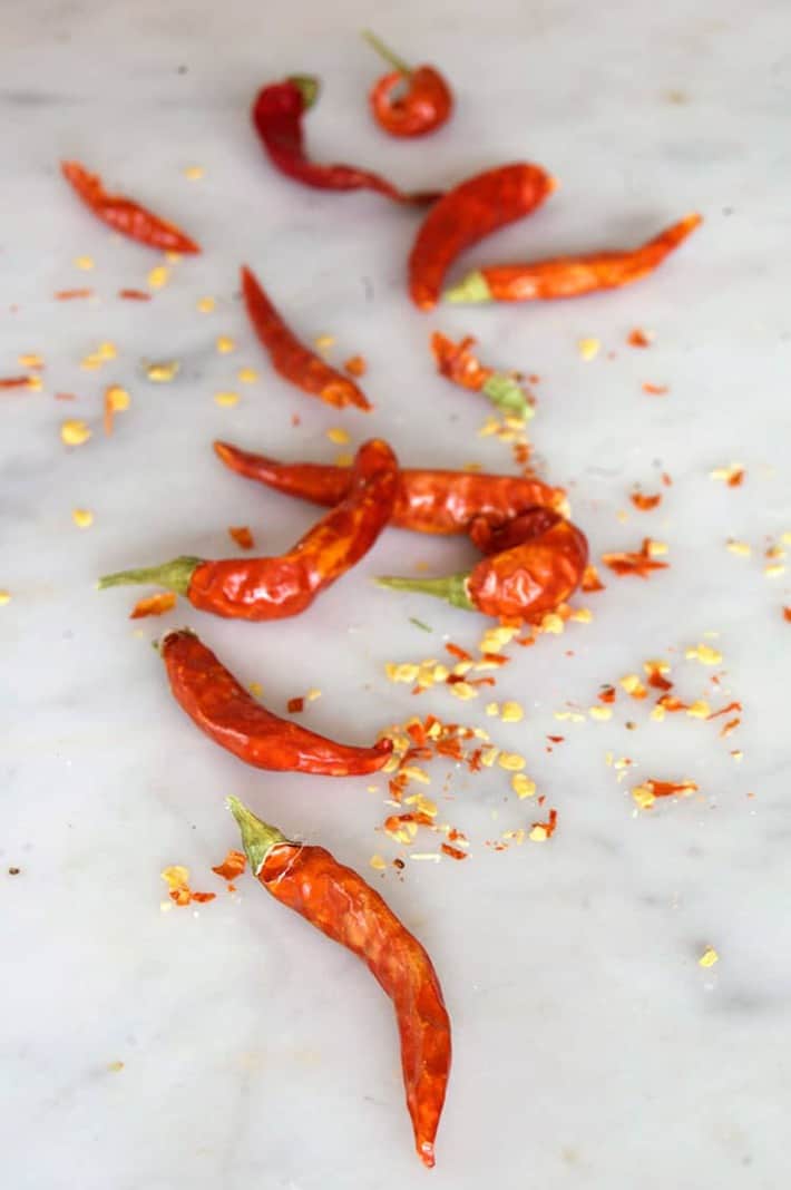 Hot dried peppers and seeds on marble counter.