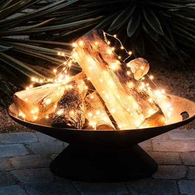A small outdoor firepit filled with wood and wire lights to give the illusion of fire.