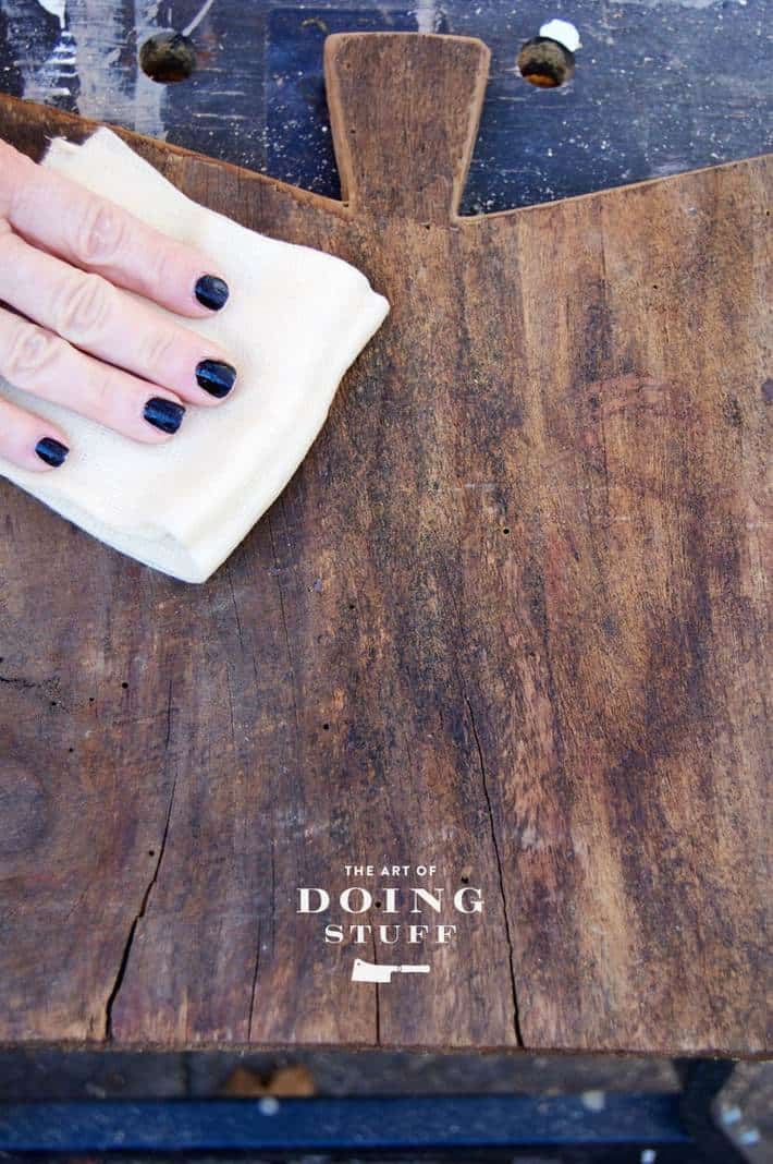 Wiping sawdust off of newly made cheese board with a tack cloth.