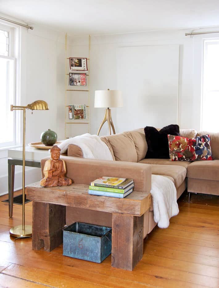 Magazine Rack made of gold chain and dowel hanging in corner of cozy living room.