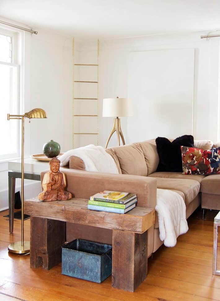 Ecclectic, cozy, white living room with gold chain and dowel magazine rack hanging from the ceiling.