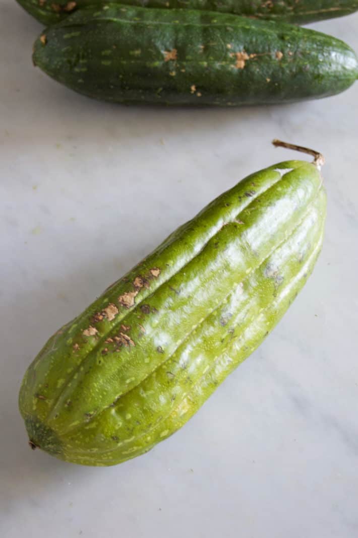 Unpeeled, green, homegrown loofah sponge.