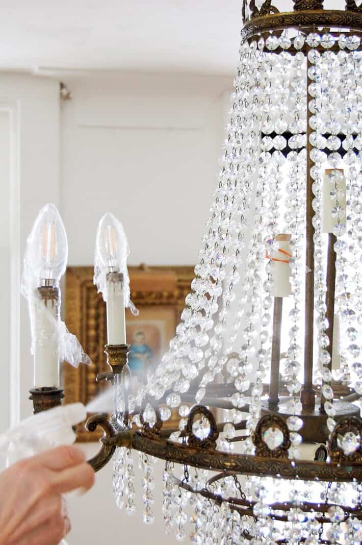 Spraying crystal chandelier with cleaner.