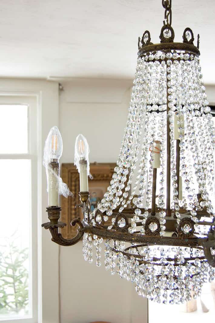 Crystal chandelier with plastic wrap covering the light sockets.