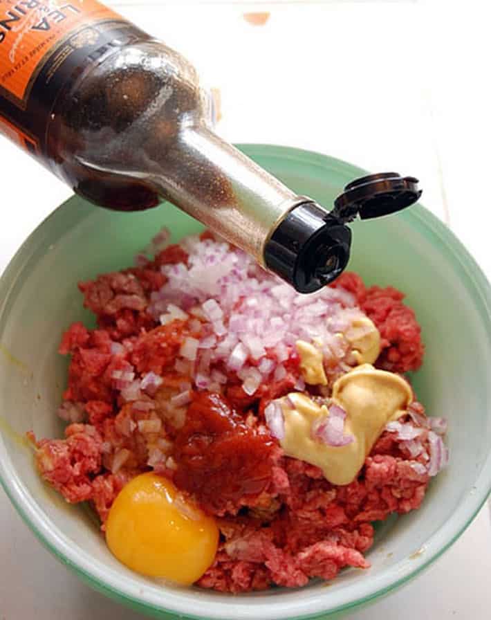 Delicious homemade hamburgers. Not fancy but not plain either. Just perfect. Splash of Worcestershire sauce dripping into green bowl with all other hamburger ingredients.