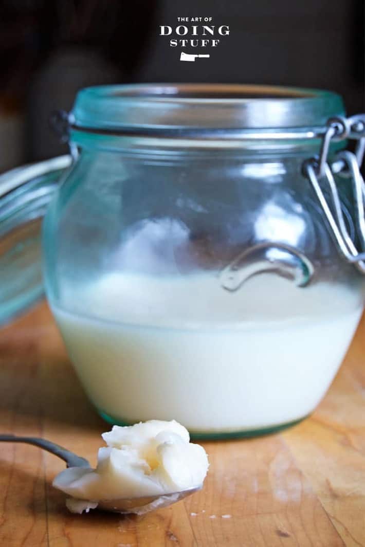 White homemade leaf lard on a spoon set on a butcher block countertop.