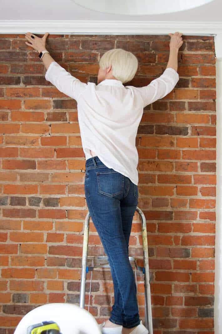 Karen Bertelsen installing LED strip lights under crown moulding.