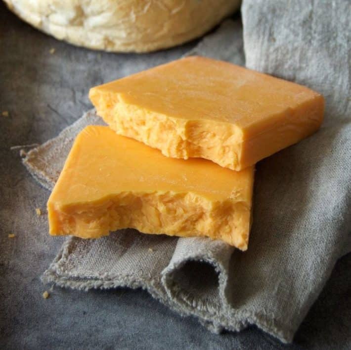 7 of the tastiest cheese options for your burger. Cheddar cheese, the classic burger cheese, laying on a linen napkin.