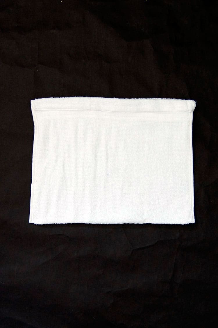 White towel with sides sewn up and top rolled down to make a casing for string or ribbon.