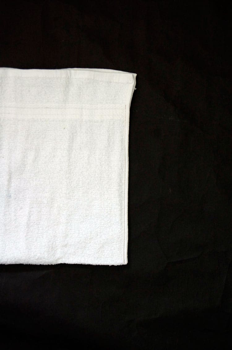 Edges of white terrycloth towel sewn together to form bag.