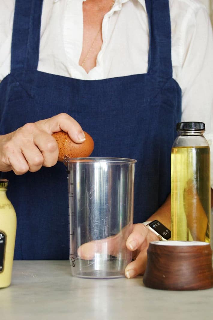 Cracking egg on side of clear immersion blender jar.