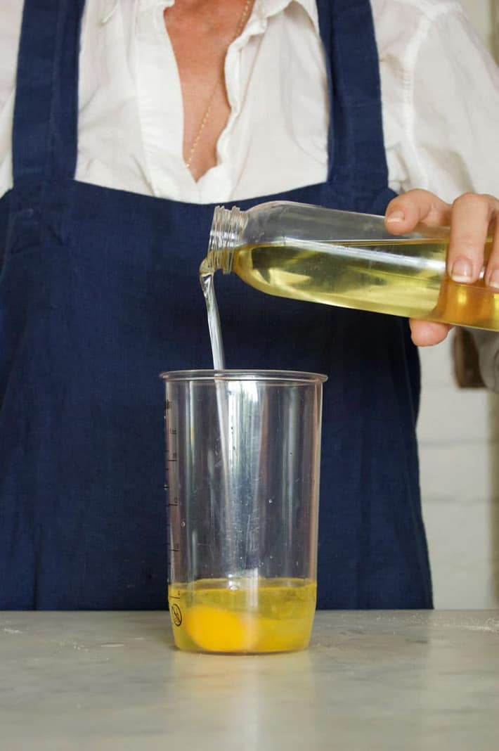 Vegetable oil being poured into clear jar to make mayo from scratch.