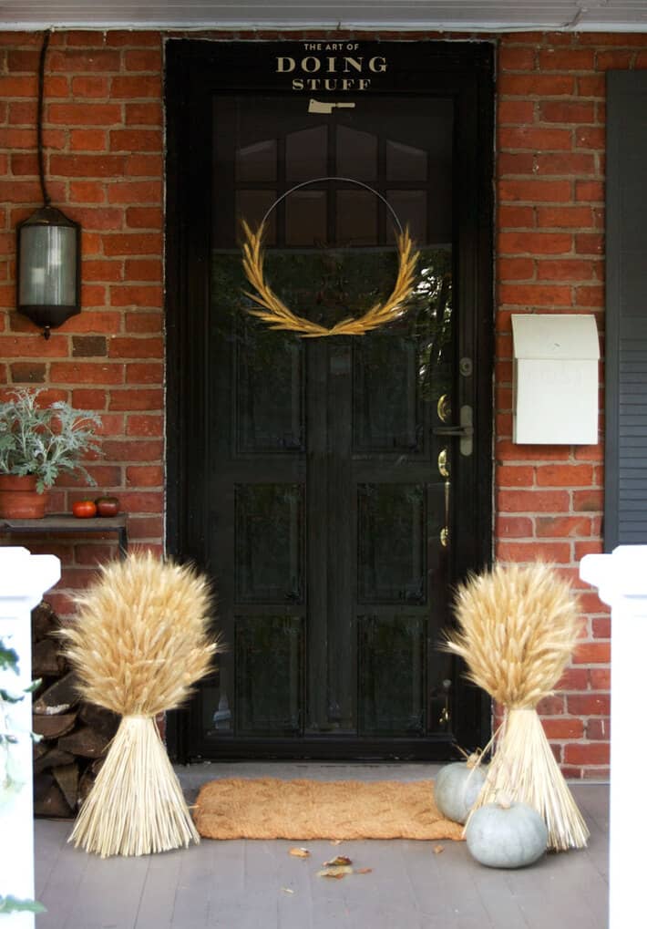 Simple DIY wheat wreath hangs on a black heritage home door.