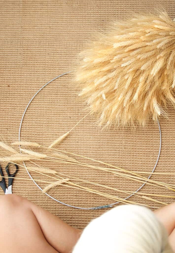 Overhead view of wheat and wire for making wreath on a sisal mat.