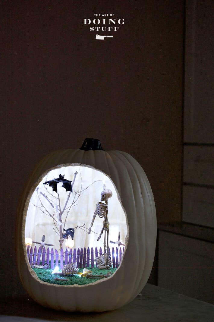A hollow foam pumpkin with an entire graveyard scene including skeletons and bats inside all lit up.