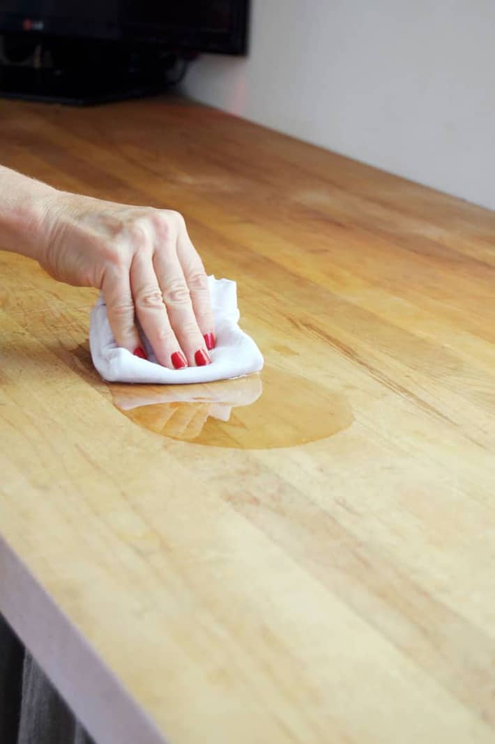 Wiping mineral oil into a wood counter to condition it.