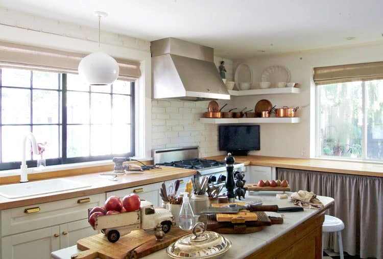 Getting ready to treat butcher block counters in a modern country kitchen with white brick walls and shaker cabinets.