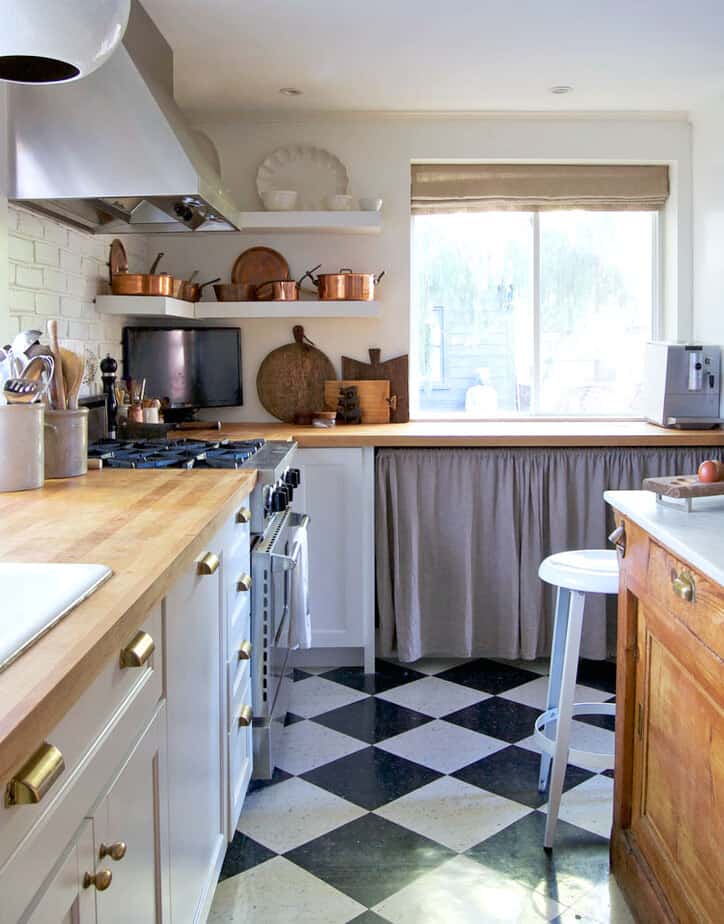 Modern country kitchen with black and white check floors, white shaker cabinets and a ruffled curtain under counter.