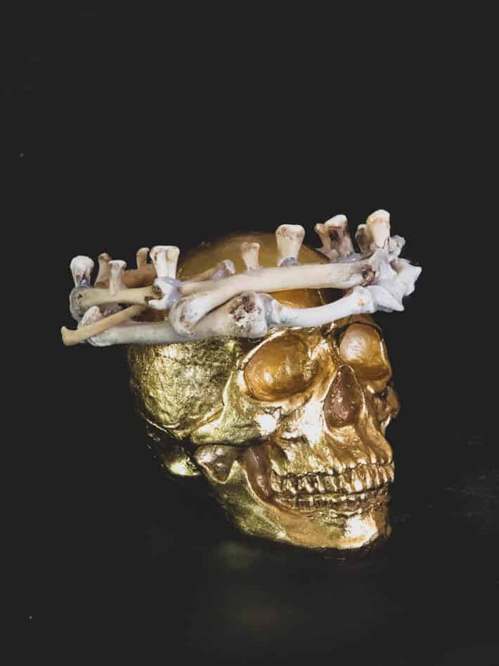 Gold skull with real DIY bone crown on black background.