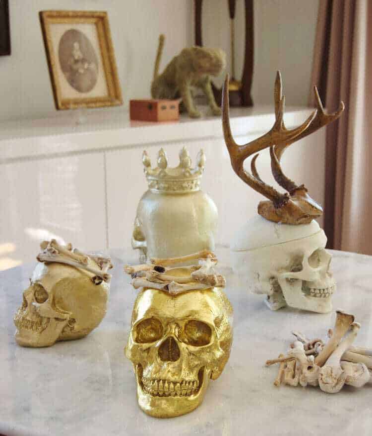 Several skulls displayed on marble table with white lacquer buffet in background.