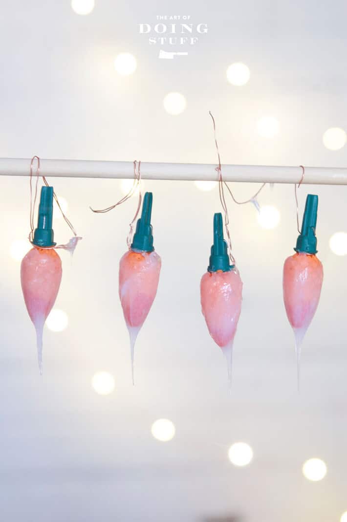 4 LED Christmas bulbs hanging from a wire to let silicone "flame" dry overnight.