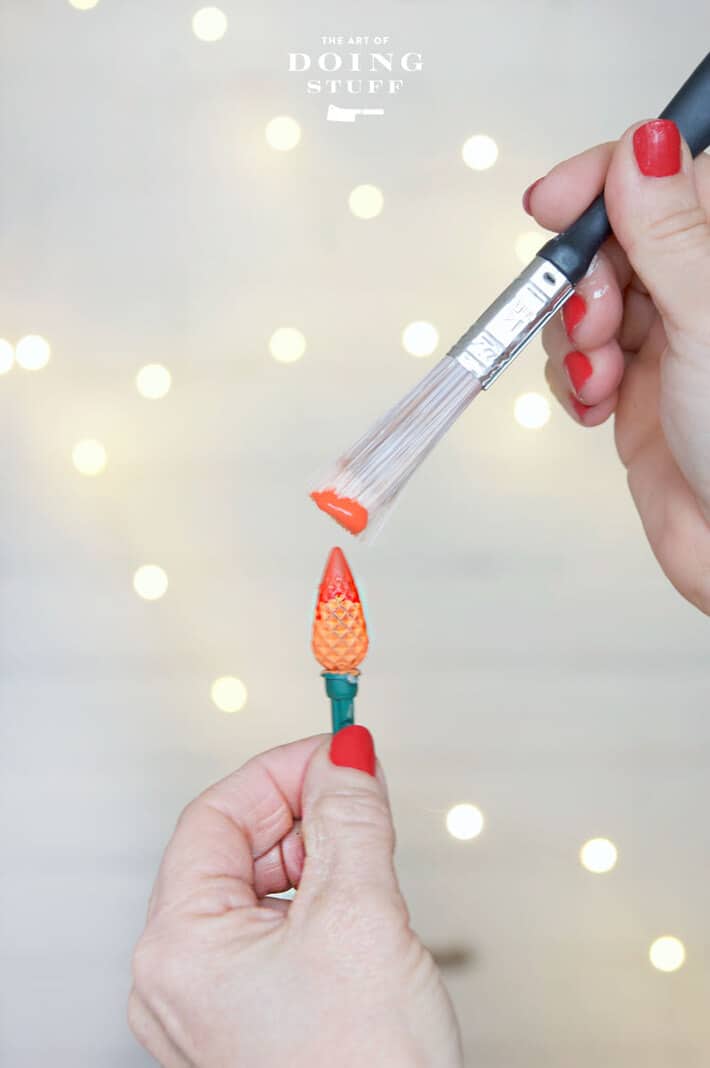 Applying orange paint to tip of led Christmas bulbs to give candlelight glow.