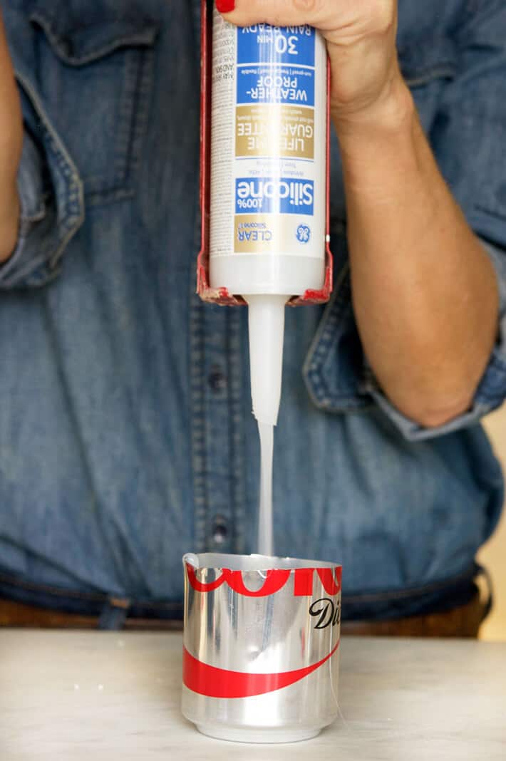 Squeezing silicone into a tin pop can.