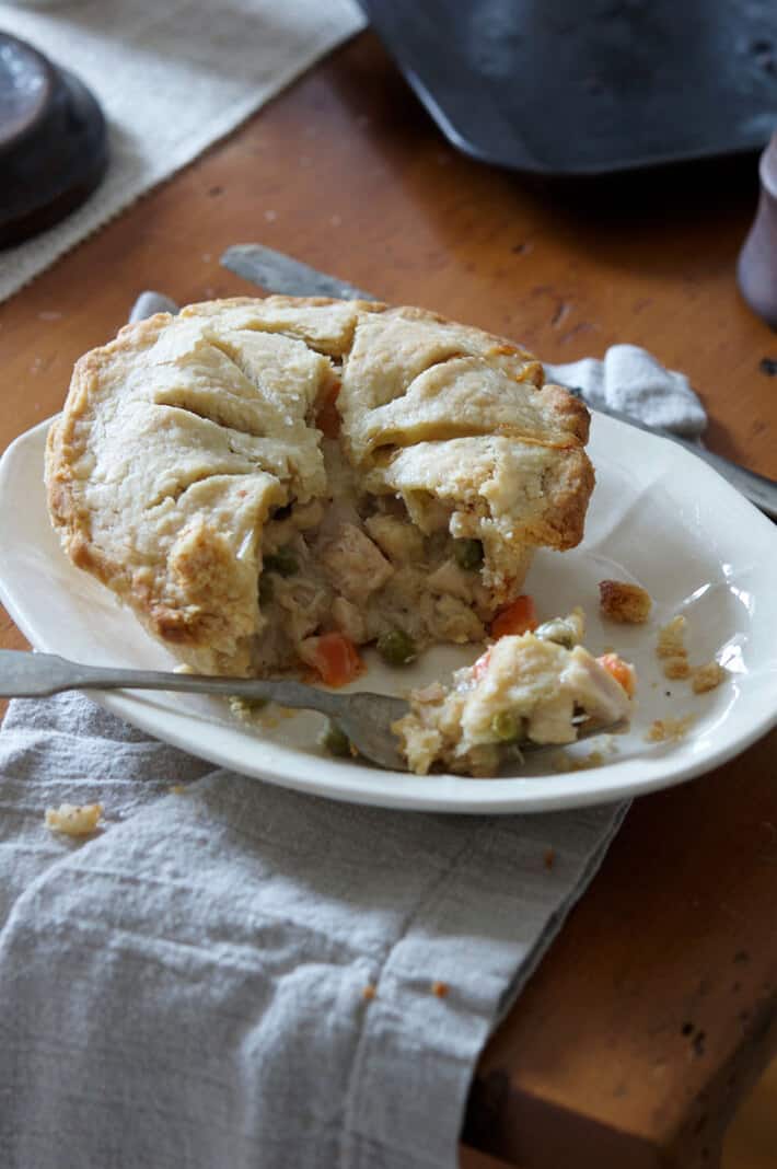 Fork full of turkey pot pie covered in flakey pastry and oozing gravy and vegetables.