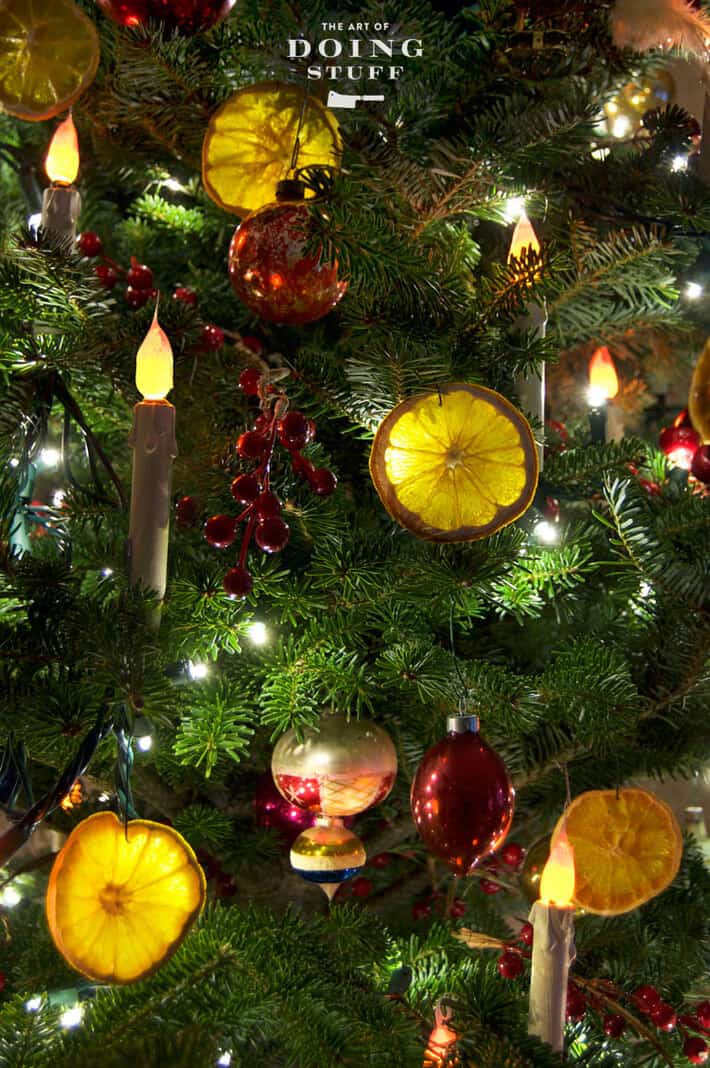 Flameless candles on Christmas tree branches decorated with dried orange slices.