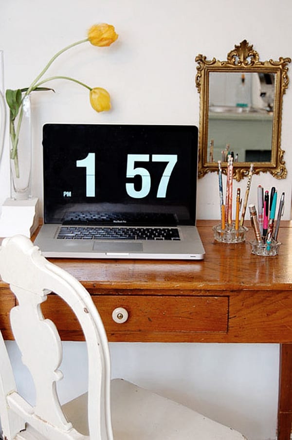 Macbook pro sits on vintage pine table with ornate gold mirror on wall.