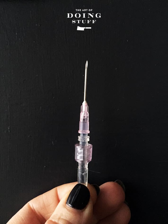 A subcutaneous fluid needle shown against a black background.