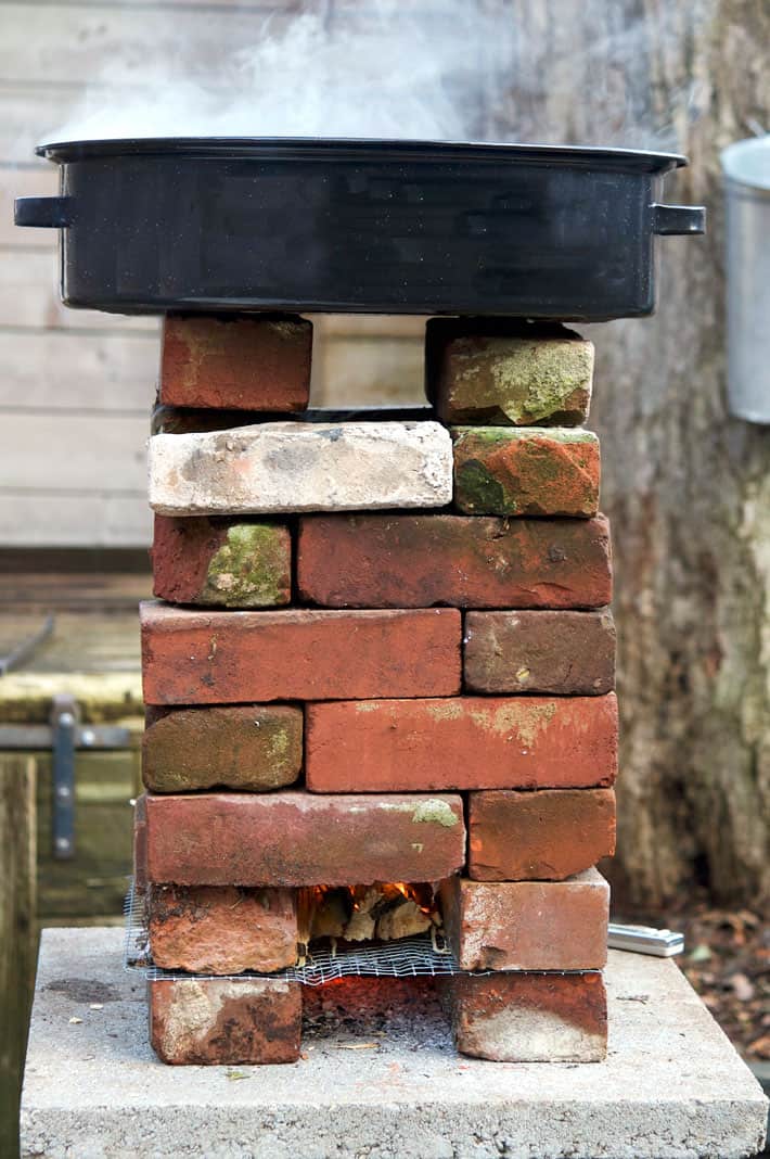 A homemade brick rocket stove with sap pan heating on top.