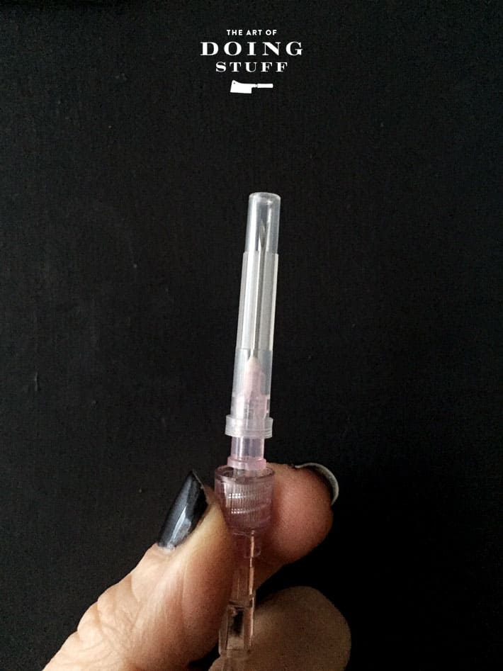 New needle with cap still on, attached to IV fluid line for cats.