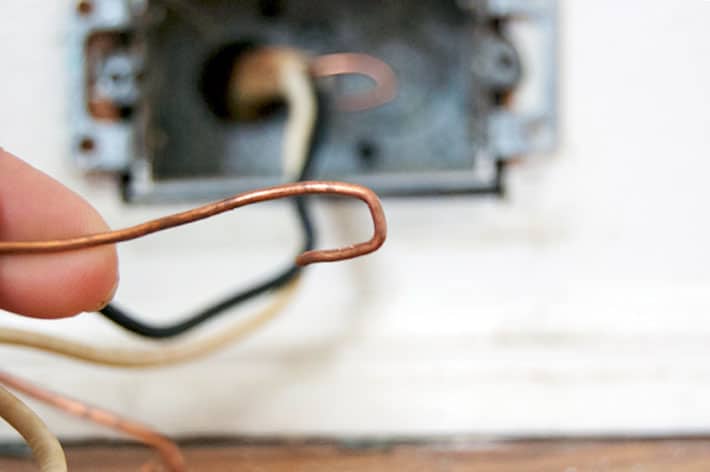 End of copper wire bent in the shape of a U for placement over ground screw.