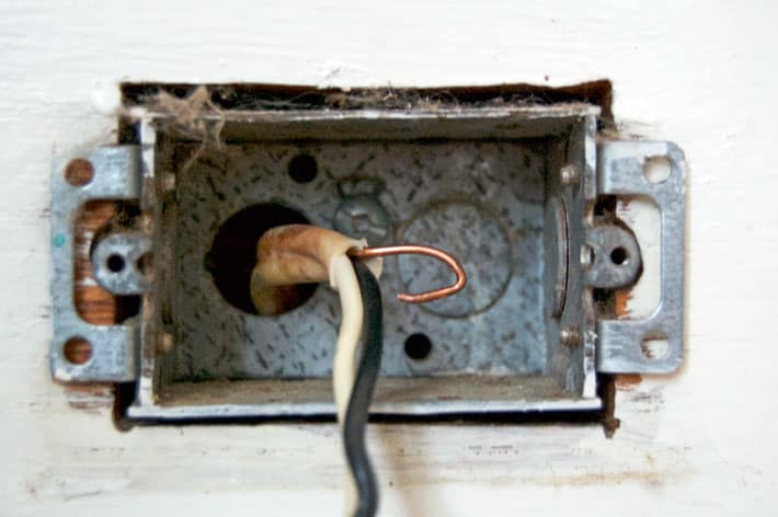 Electrical wires coming into electrical box, with ground wire bent in a U for placement over the ground screw.