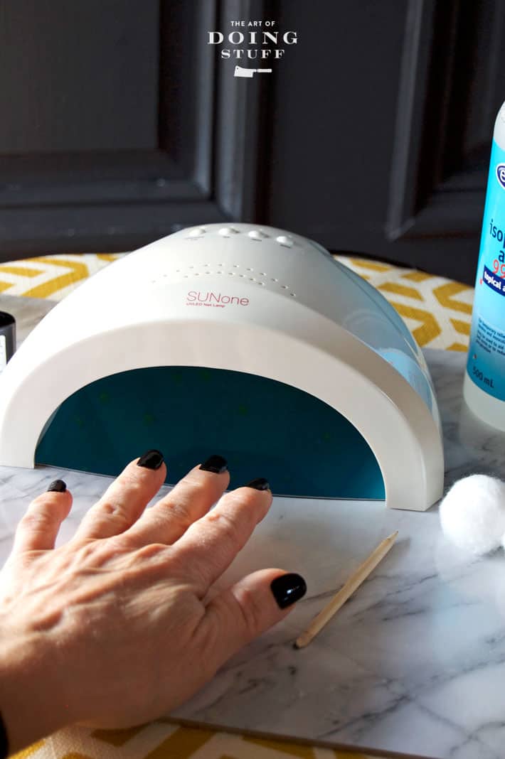 Putting hand with black polish into LED nail lamp.